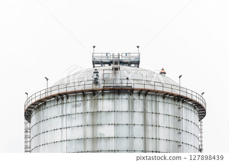 Giant liquefied natural gas storage tank with a domed roof is dominating the landscape, showcasing the scale of industrial infrastructure 127898439