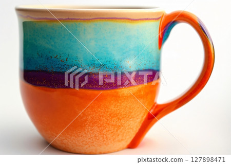 Colorful handmade ceramic mug is standing on a white background, showcasing its unique and vibrant design 127898471