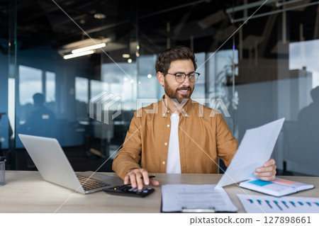 Successful businessman doing paperwork inside office. Male financier accountant checking tax reports, using calculator at workplace, satisfied with company results. Successful businessman doing paperwork inside office. Male financier accountant checking tax reports, using calculator at workplace, satisfied with company results. 127898661