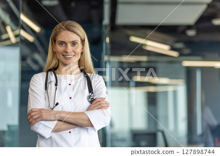 Confident female doctor with stethoscope standing arms crossed in modern medical office. Professional expression exudes trust, competence, dedication. Ideal for healthcare, medical, professional Confident female doctor with stethoscope standing arms crossed in modern medical office. Professional expression exudes trust, competence, dedication. Ideal for healthcare, medical, professional 127898744