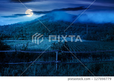 mountain landscape of ukraine with rural field in summer at foggy night. beautiful countryside scenery with forest on the hill in full moon light. mysterious view of a agriculture scene mountain landscape of ukraine with rural field in summer at foggy night. beautiful countryside scenery with forest on the hill in full moon light. mysterious view of a agriculture scene 127898779