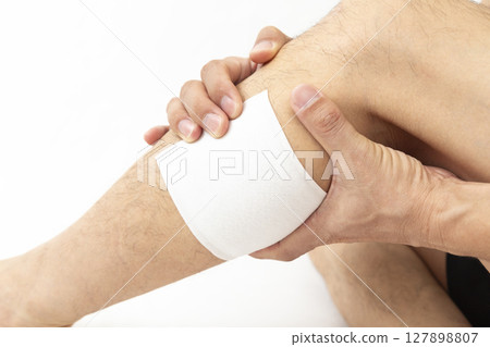 Man applying a compress to his calf, white background Man applying a compress to his calf, white background 127898807