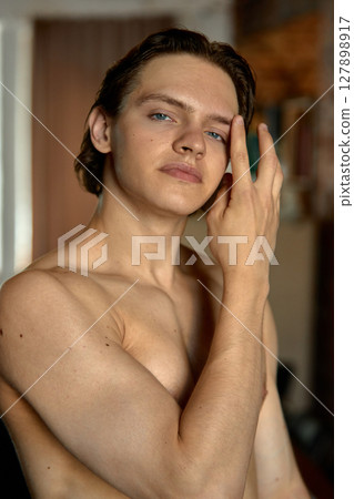 Confident young man posing indoors with soft natural lighting 127898917