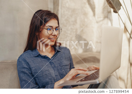 A young woman diligently works on her laptop in a cozy, inspiring setting for creativity 127899454