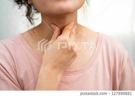 Asian woman touching her neck and throat for thyroid gland problem. 127899881