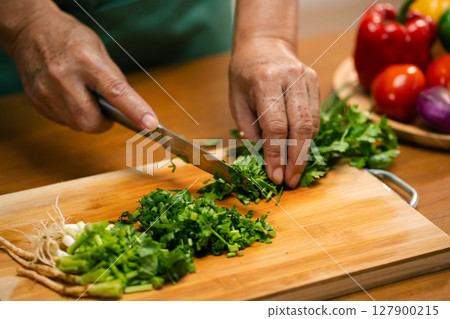 Asian man's hands chopping coriander in the kitchen Asian man's hands chopping coriander in the kitchen 127900215