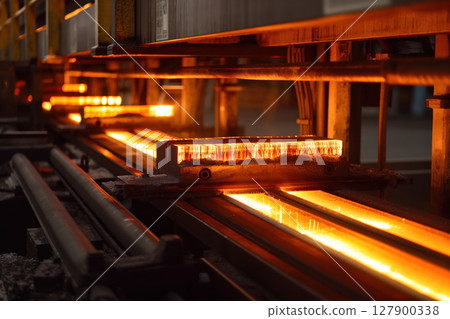 Aluminum profiles glowing hot coming out of an aluminum extrusion press machine at a factory 127900338