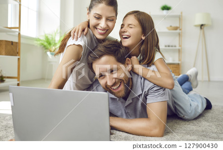 Portrait of happy loving family using laptop while spending time together at home in living room. Portrait of happy loving family using laptop while spending time together at home in living room. 127900430