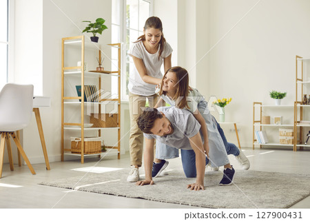 Happy kid girl having fun with her family sitting on father's back at home. Happy kid girl having fun with her family sitting on father's back at home. 127900431