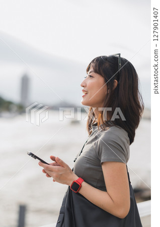 Happy young southeast asian woman, teenager blogger searching map smartphone, tourism guide. World travel explorer local cultural experience concept Chao Phraya river, Bangkok, Thailand, Asia Happy young southeast asian woman, teenager blogger searching map smartphone, tourism guide. World travel explorer local cultural experience concept Chao Phraya river, Bangkok, Thailand, Asia 127901407
