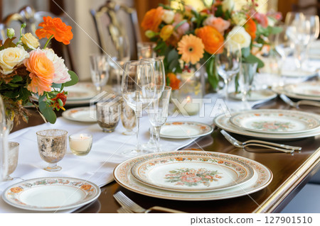 Elegant table setting with orange flowers and candles, creating a warm and inviting ambiance for a special occasion Elegant table setting with orange flowers and candles, creating a warm and inviting ambiance for a special occasion 127901510