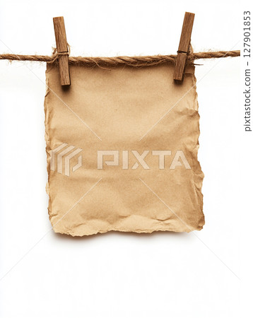 brown paper sheets hang on a string with wooden clothespins against a white background. 127901853