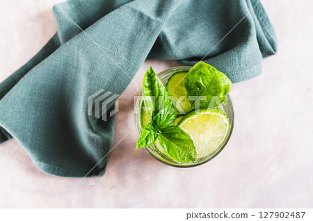 Close up of spa spritz with cucumber, lime and basil in a glass on the table top view 127902487