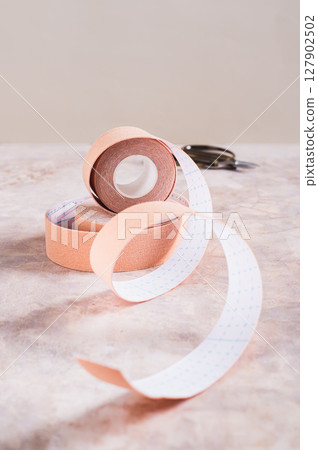 Modern trend against aging and wrinkles kinesio tape in a roll on the table vertical view 127902502