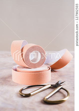 Neutral colored kinesio tapes for face lifting and scissors on the table web banneer Neutral colored kinesio tapes for face lifting and scissors on the table web banneer 127902503