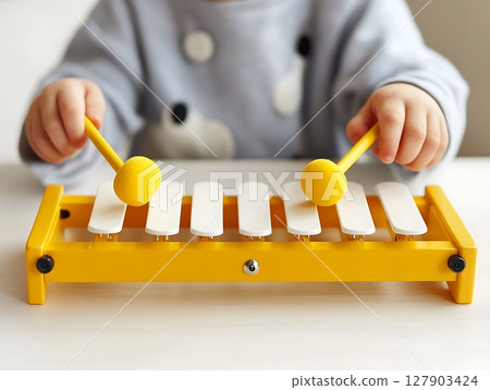 Child Playing Yellow Xylophone with Mallets in Fun Activity 127903424