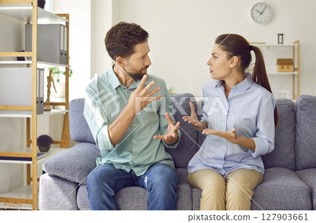 Young couple sitting at home and arguing in the living room. Quarrel and divorce concept. Young couple sitting at home and arguing in the living room. Quarrel and divorce concept. 127903661