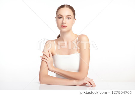 A beautiful young woman with clean, fresh skin against a white background. Skincare, facial treatment, cosmetology, beauty, and spa. An elegant portrait of an woman. 127904705