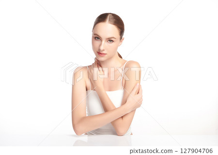 A beautiful young woman with clean, fresh skin against a white background. Skincare, facial treatment, cosmetology, beauty, and spa. An elegant portrait of an woman. 127904706