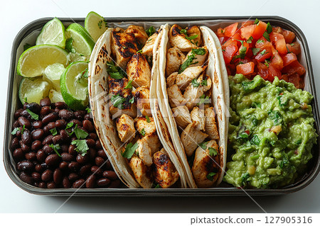 Taco inspired lunch box with black beans, guacamole, grilled chicken and corn tortillas. Mexican lunch box. Taco inspired lunch box with black beans, guacamole, grilled chicken and corn tortillas. Mexican lunch box. 127905316