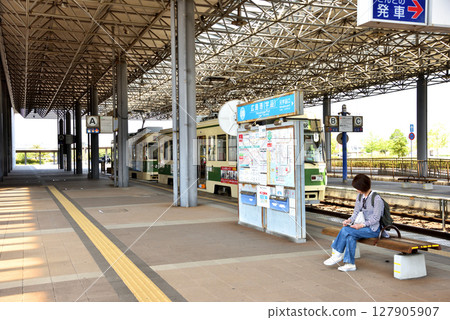 A woman waiting for a tram at Hiroshima Port Station 127905907