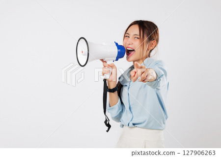 A happy young Asian woman points with her finger on camera, shouting into megaphone to announce news. She is excited to speak through this speaker, a clear megaphone. isolated studio white background A happy young Asian woman points with her finger on camera, shouting into megaphone to announce news. She is excited to speak through this speaker, a clear megaphone. isolated studio white background 127906263