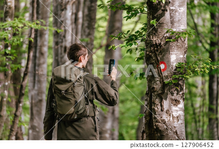 Man Walking in Forest Taking Picture with Phone 127906452