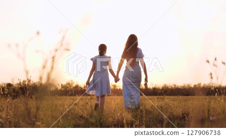 mother daughter walking field sunset holding hands, happy family, child loves mother, holding parent hand sunset, happy people nature, mother daughter outdoors, family vacation nature, walking 127906738