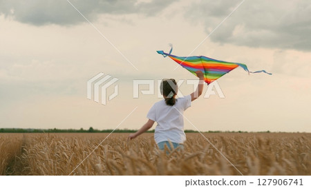 concept happy childhood. Little girl schoolgirl, fly kites into sky, field wheat sunset. child happily runs through field wheat. Children kite game. concept child dream. Children imagination dream concept happy childhood. Little girl schoolgirl, fly kites into sky, field wheat sunset. child happily runs through field wheat. Children kite game. concept child dream. Children imagination dream 127906741