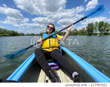 Happy woman in kayak with paddle, summer day, kayaking on the river. 127907022