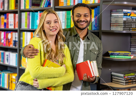 Smiling contented couple at the library reading books Smiling contented couple at the library reading books 127907120