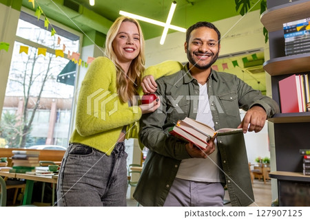 Smiling contented couple at the library reading books 127907125