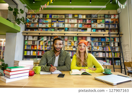 Two young people sitting at the table at the library Two young people sitting at the table at the library 127907163
