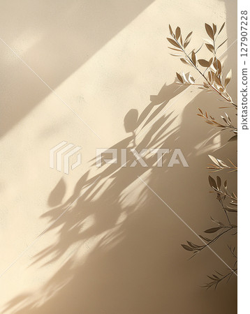Shadows cast by delicate leaves create a serene atmosphere on a warm-toned wall 127907228