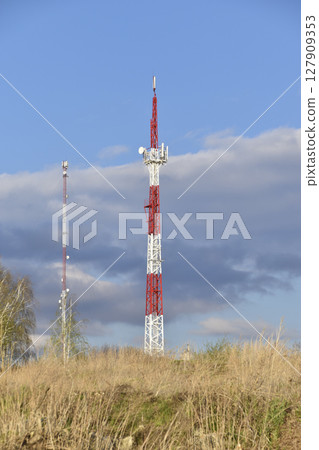 The communication tower is painted in red and white. A communications tower in rural areas. 127909353