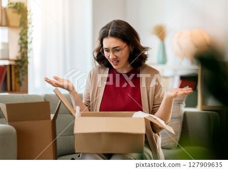 Woman is unpacking cardboard Woman is unpacking cardboard 127909635