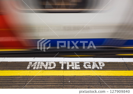Blurry London Underground Train Passes MIND THE GAP Warning on Platform Edge, UK Transit Safety Blurry London Underground Train Passes MIND THE GAP Warning on Platform Edge, UK Transit Safety 127909840