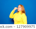Caucasian woman in her 40s wearing a yellow sweater with a positive and happy smile showing a delicious perfect gourmet sign isolated over blue colored background 127909975