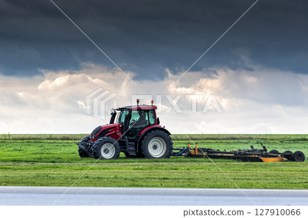 Wheel tractor with lawn mower by the road Wheel tractor with lawn mower by the road 127910066