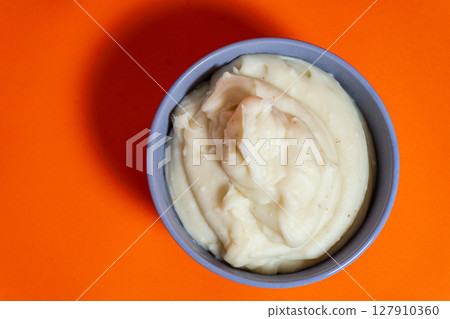 Creamy mashed potatoes served in a bowl on vibrant orange background Creamy mashed potatoes served in a bowl on vibrant orange background 127910360