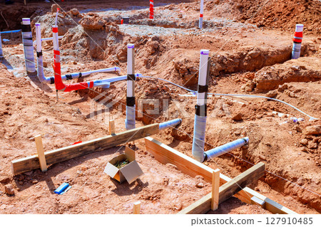 Workers are laying out wastewater plumbing pipes in freshly dug construction site during work day 127910485