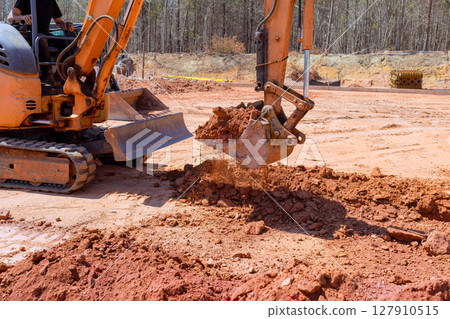 Excavator operates efficiently at construction site, digging deep soil industrial productivity machinery power. 127910515