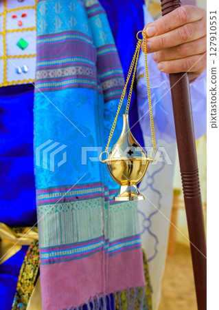 Cultural celebration features a performer in traditional dress holding an elegant gold incense burner. Cultural celebration features a performer in traditional dress holding an elegant gold incense burner. 127910551