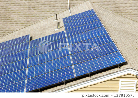 Solar panels cover roof of home, capturing sunlight for energy generation in suburban setting. 127910573