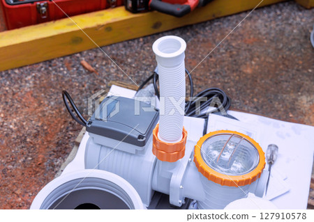 Technicians work on setting up water pump system to swimming pool in backyard, preparing for plumbing needs 127910578