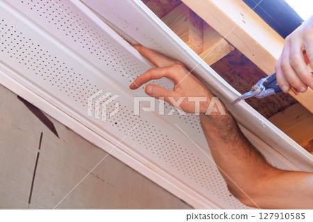 Worker install new panel ceiling siding during home renovation as works day Worker install new panel ceiling siding during home renovation as works day 127910585