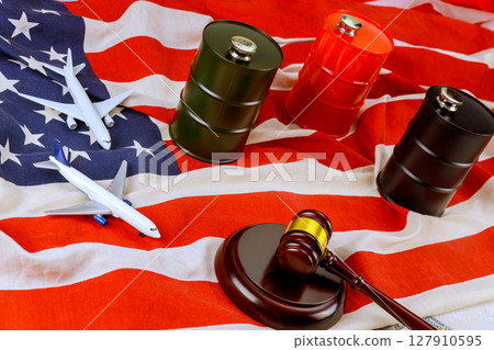 Models of airplanes oil barrels arranged with judicial gavel on American flag, symbolizing trade, legislation 127910595