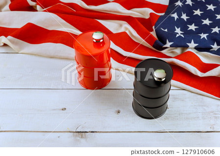 Fuel barrels sit on folded American flag, showcasing contrasting colors against rustic background. Fuel barrels sit on folded American flag, showcasing contrasting colors against rustic background. 127910606