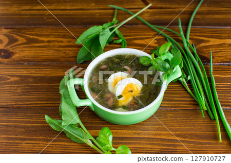 Homemade green borscht with boiled egg and fresh sorrel on a dark wooden table Homemade green borscht with boiled egg and fresh sorrel on a dark wooden table 127910727