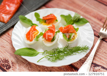 Cold festive appetizer of eggs with fish slices 127910751